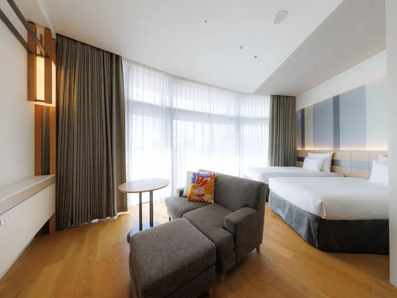 Une chambre lumineuse avec un canapé et deux lits simples.