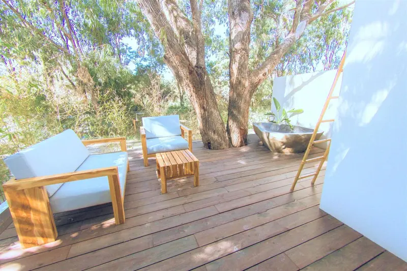 Terrasse en bois avec mobilier de jardin et baignoire extérieure.