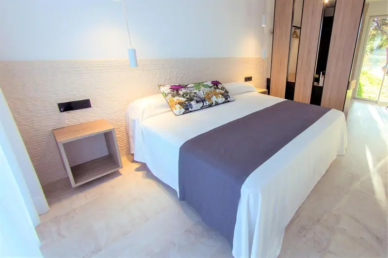Une chambre lumineuse avec un grand lit recouvert d'une couverture florale.