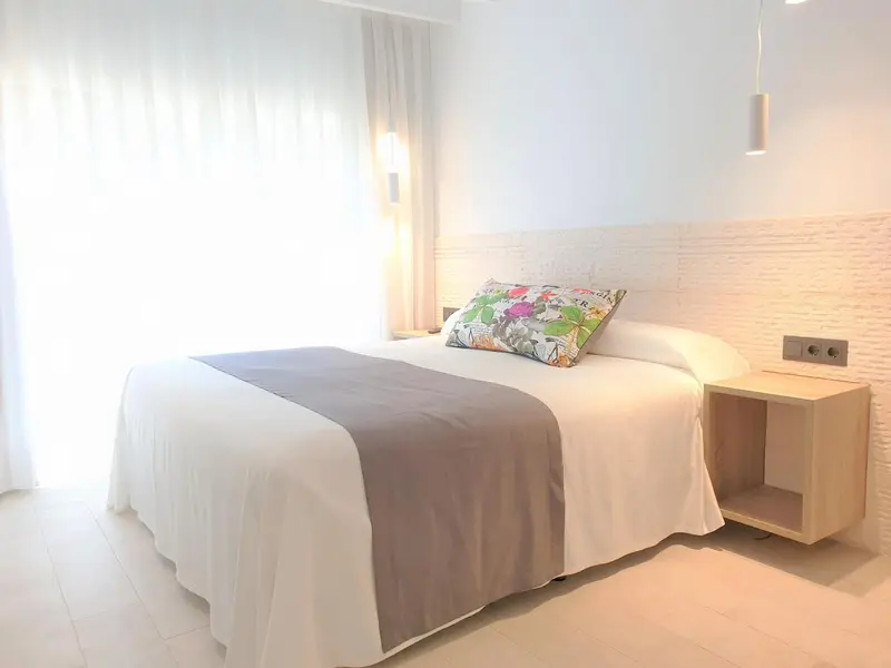 Une chambre lumineuse avec un grand lit recouvert d'une courtepointe.
