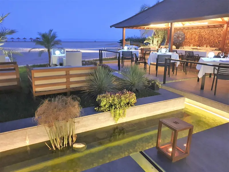Terrasse de restaurant en bord de mer illuminée au crépuscule.