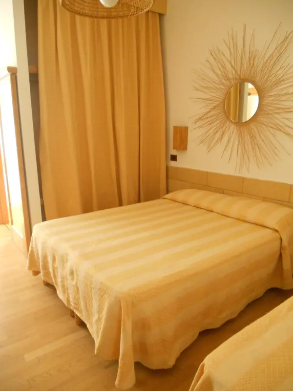 Une chambre lumineuse avec un lit recouvert d'une couverture rayée et une décoration murale en forme de soleil.