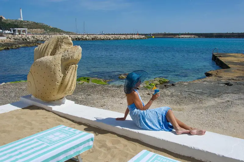 Une femme assise sur une plage regarde la mer.