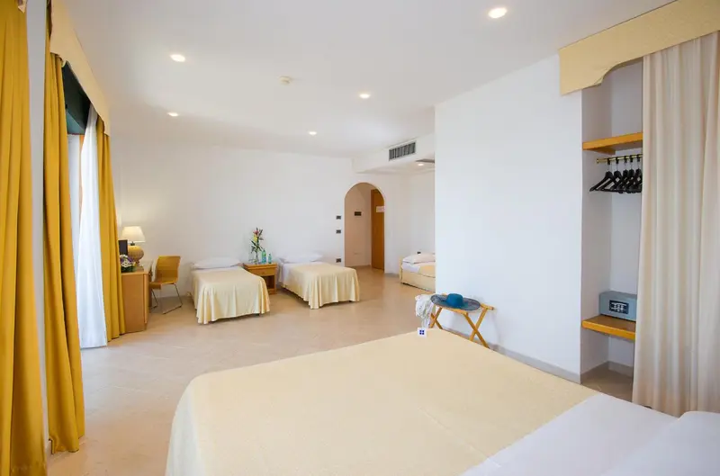 Une chambre lumineuse avec deux lits simples et un lit double.