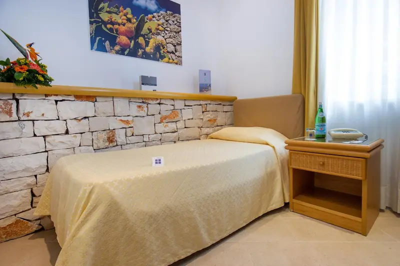 Une chambre lumineuse avec un lit simple et une table de chevet.