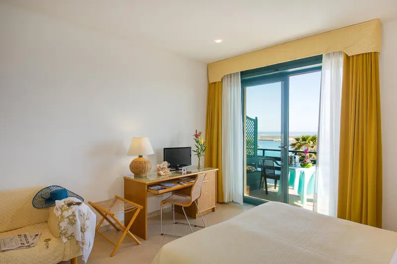 Une chambre lumineuse avec un bureau et un accès à un balcon.