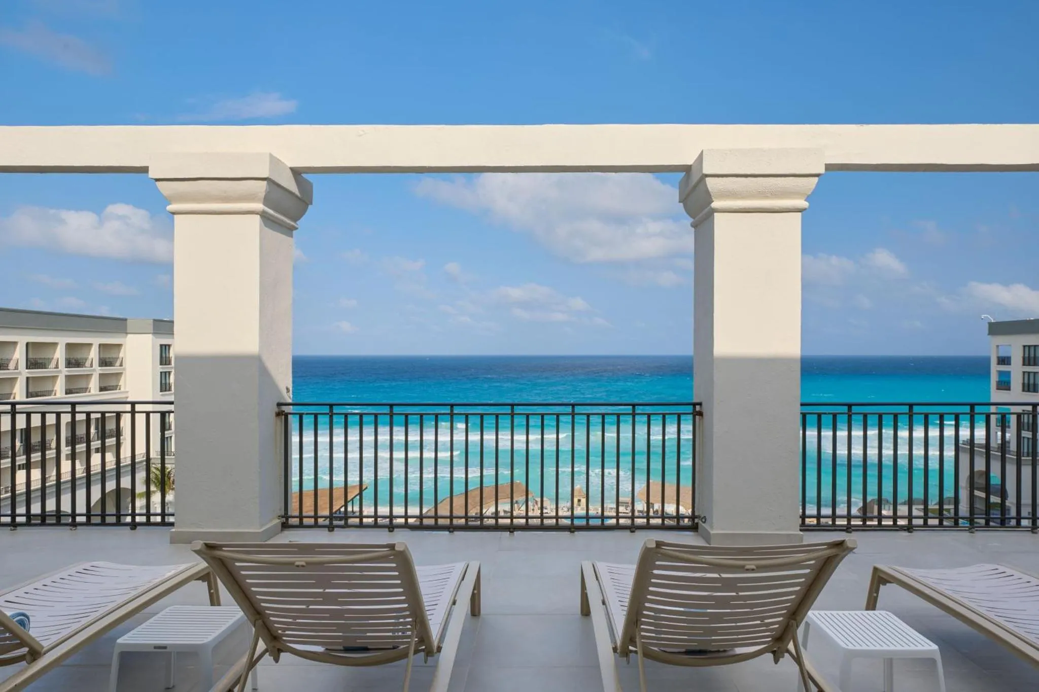 Deux transats blancs invitent à la détente sur une terrasse ensoleillée face à la mer turquoise.