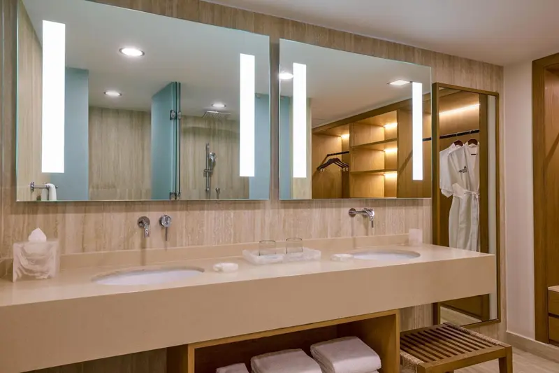 Une salle de bain lumineuse avec deux vasques et un grand miroir.