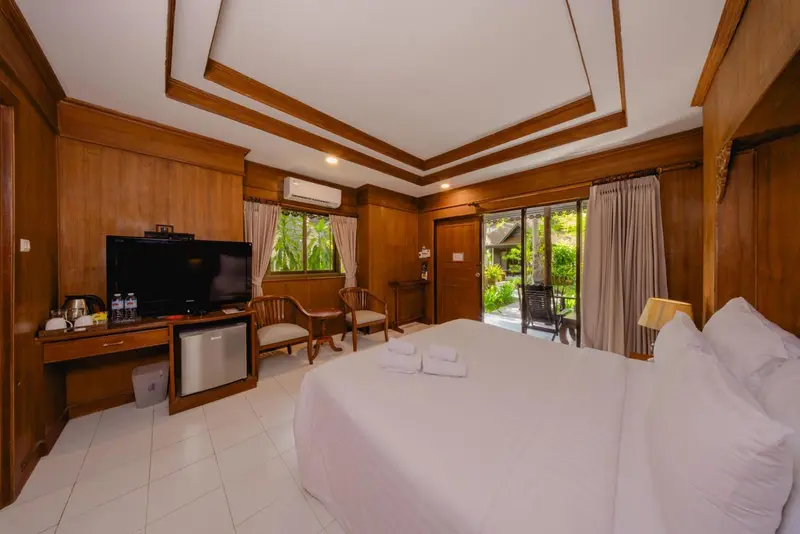 Une chambre lumineuse avec un lit blanc et un bureau en bois.