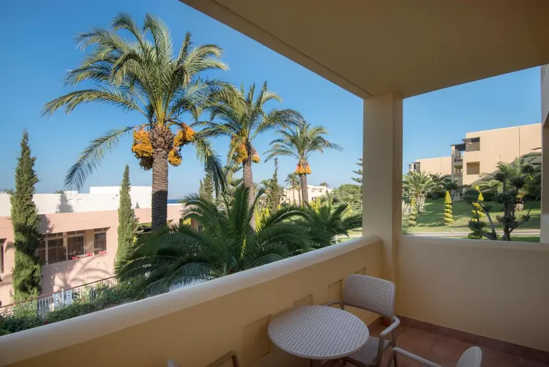 Une terrasse ensoleillée offre une vue sur la végétation luxuriante et les bâtiments environnants.