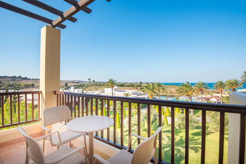 Terrasse avec mobilier de jardin donnant sur un paysage verdoyant et la mer.