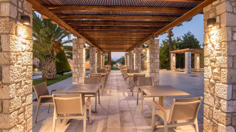 Terrasse ombragée avec tables et chaises en extérieur.