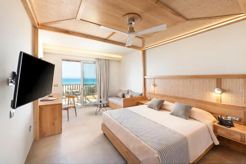Chambre lumineuse avec un grand lit et vue sur la mer.