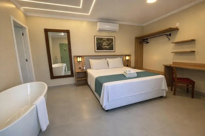 Chambre lumineuse avec un grand lit et une baignoire.