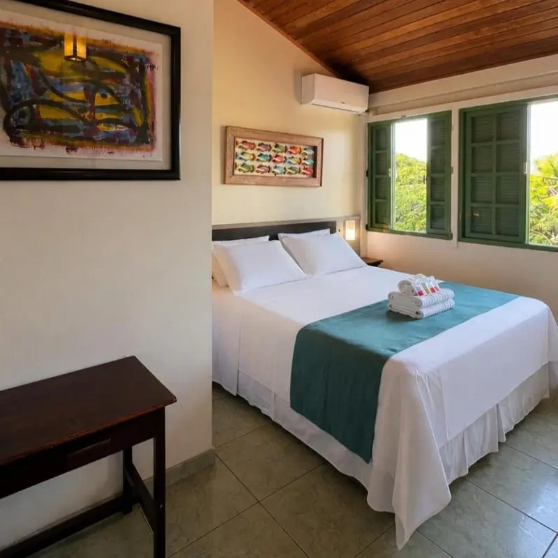 Une chambre lumineuse avec un grand lit recouvert d'une courtepointe turquoise.