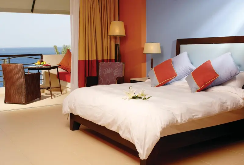 Une chambre lumineuse avec un lit et un coin repas donnant sur la mer.