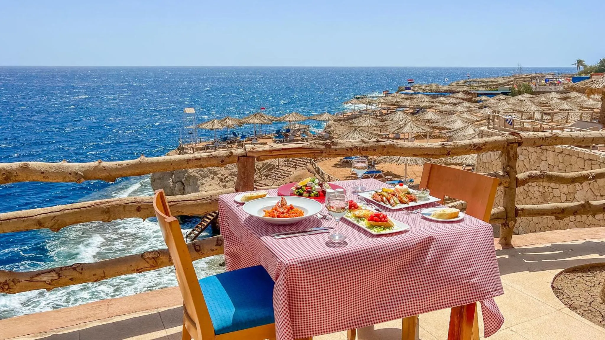 Une table dressée avec des plats et des boissons en terrasse avec vue sur la mer.
