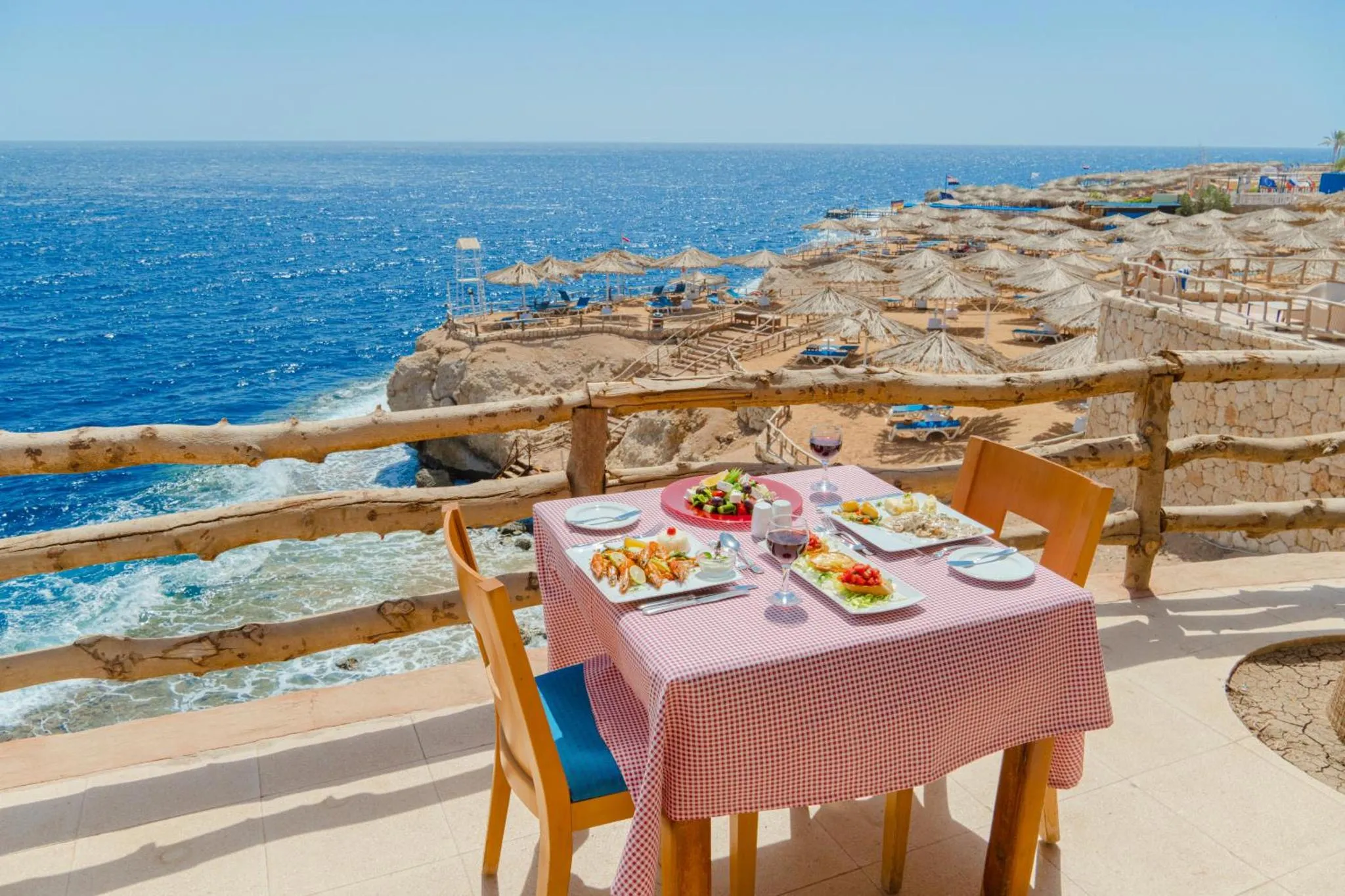 Une table dressée avec des plats et des boissons en terrasse avec vue sur la mer.