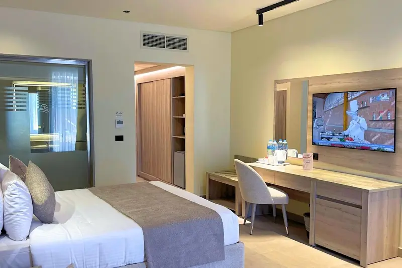 Une chambre lumineuse avec un lit fait et un espace bureau.