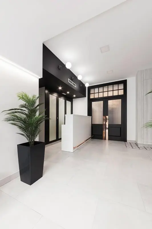 Hall d'entrée moderne avec comptoir d'accueil et plantes vertes.