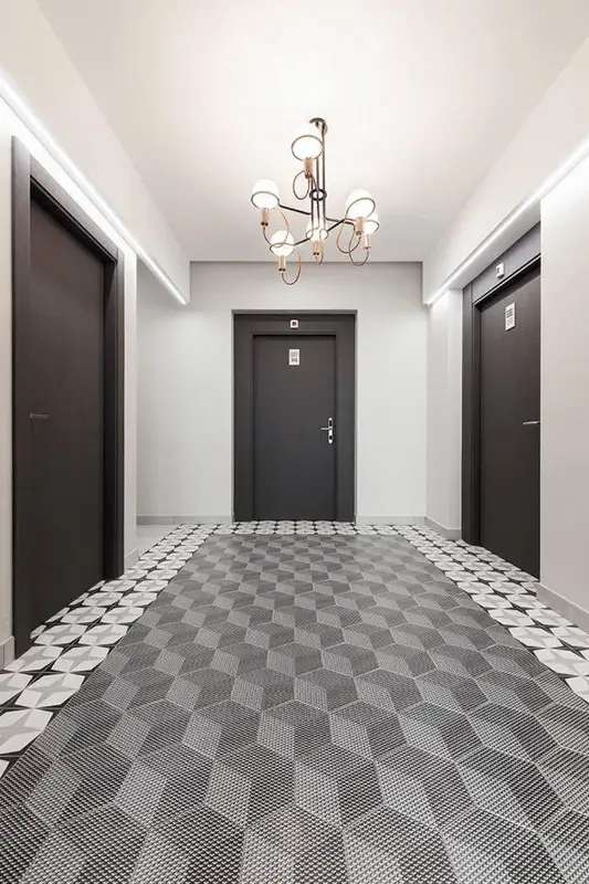 Couloir d'hôtel avec des portes et un sol à motifs géométriques.