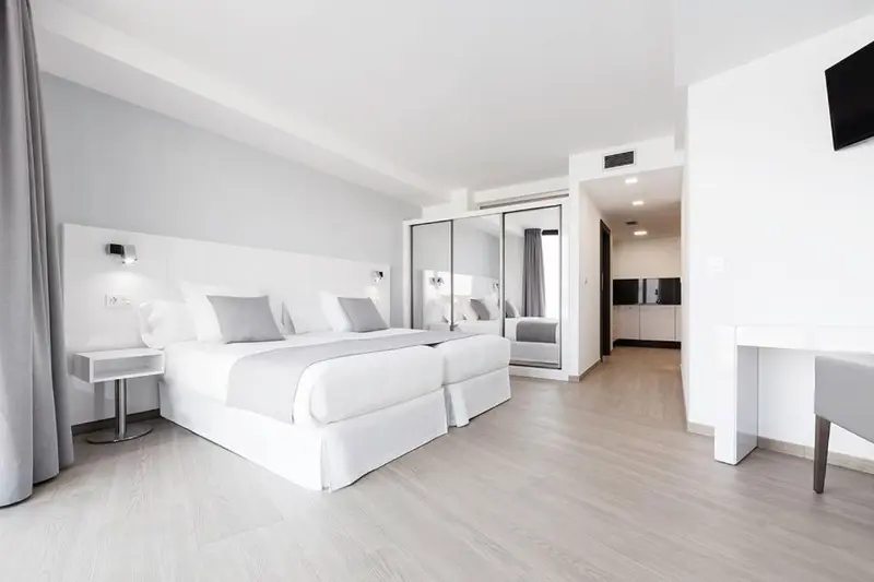Chambre lumineuse avec deux lits simples et un espace détente.