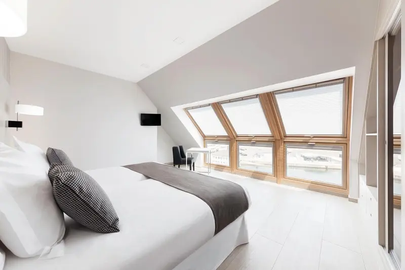 Une chambre lumineuse avec un grand lit et des fenêtres en hauteur.