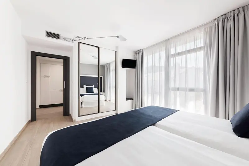 Une chambre moderne avec un grand lit et des rideaux clairs.