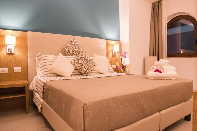 Une chambre lumineuse avec un grand lit recouvert d'une courtepointe et de coussins.