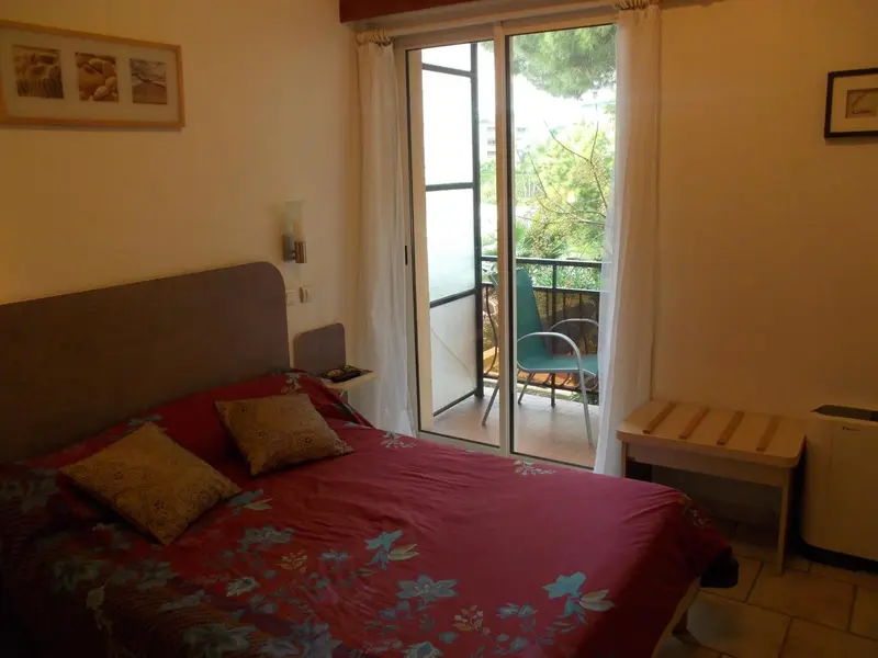 Une chambre avec un lit rouge et un accès à un balcon.