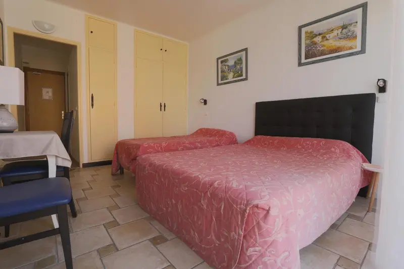 Une chambre lumineuse avec deux lits simples et un coin repas.