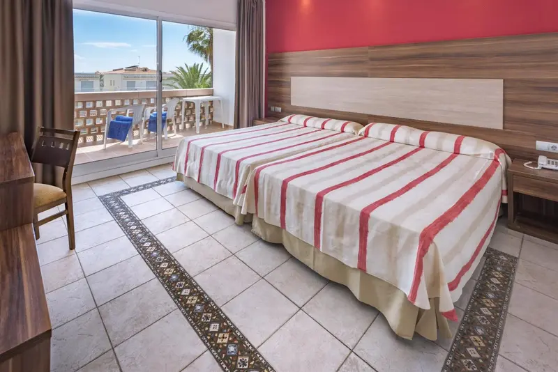 Chambre lumineuse avec un grand lit et un accès à une terrasse.