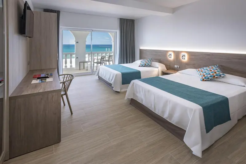Chambre lumineuse avec deux lits simples et vue sur la mer.