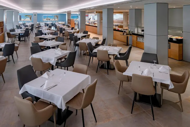 Une salle lumineuse avec des tables dressées pour un repas.