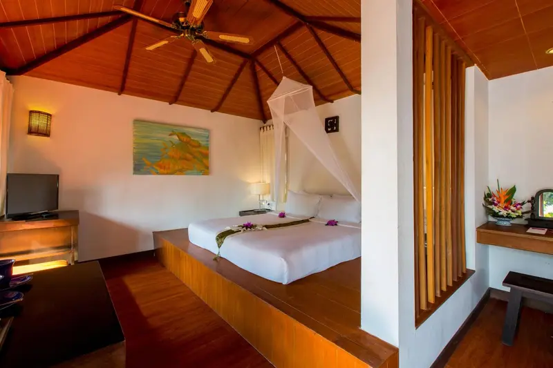 Une chambre lumineuse avec un lit à baldaquin sur une plateforme en bois.