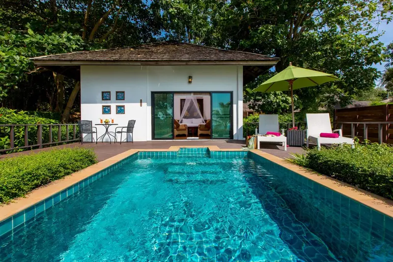 Une petite maison blanche avec une piscine privée et une terrasse ombragée.