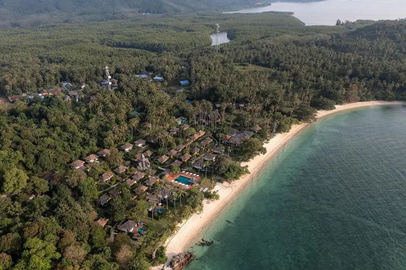 Vue aérienne d'un complexe hôtelier bordant une plage de sable fin et une végétation luxuriante.