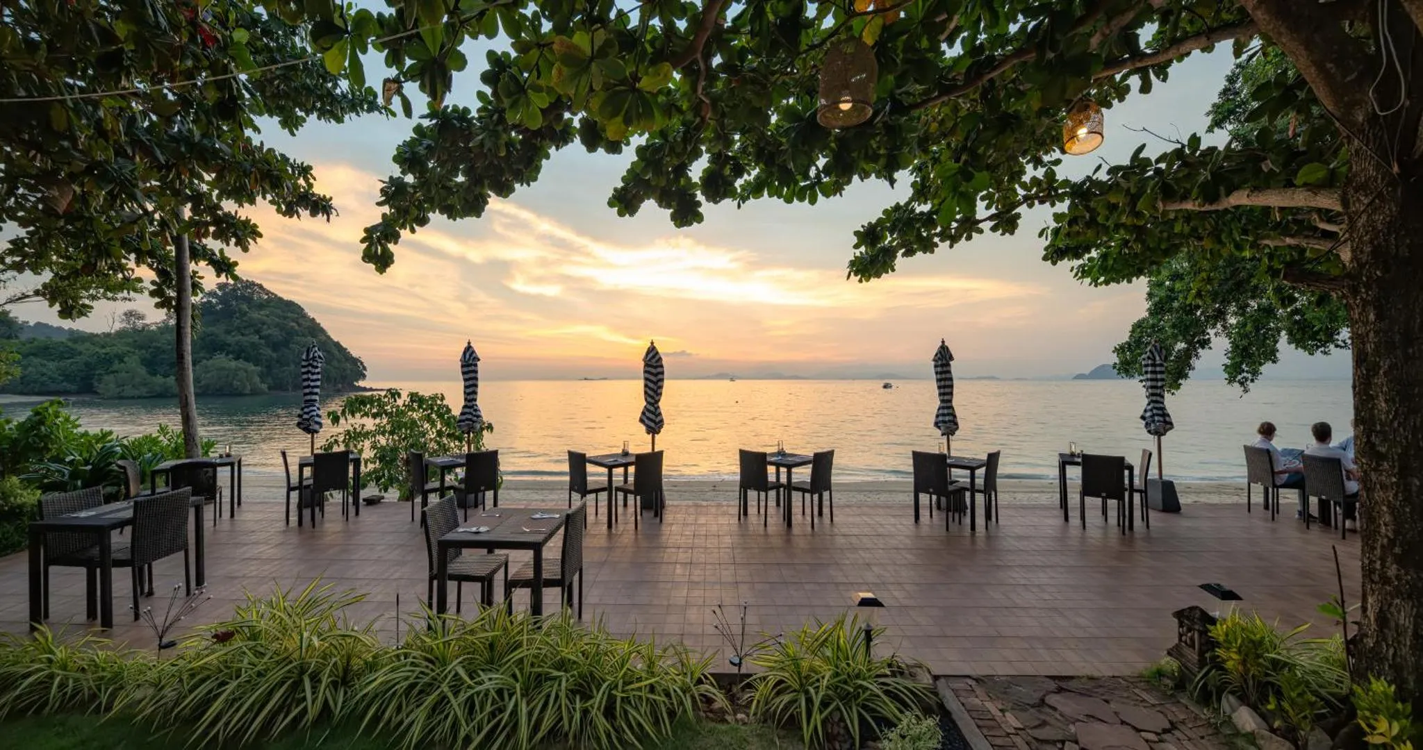 Terrasse de restaurant en bord de mer au coucher du soleil.