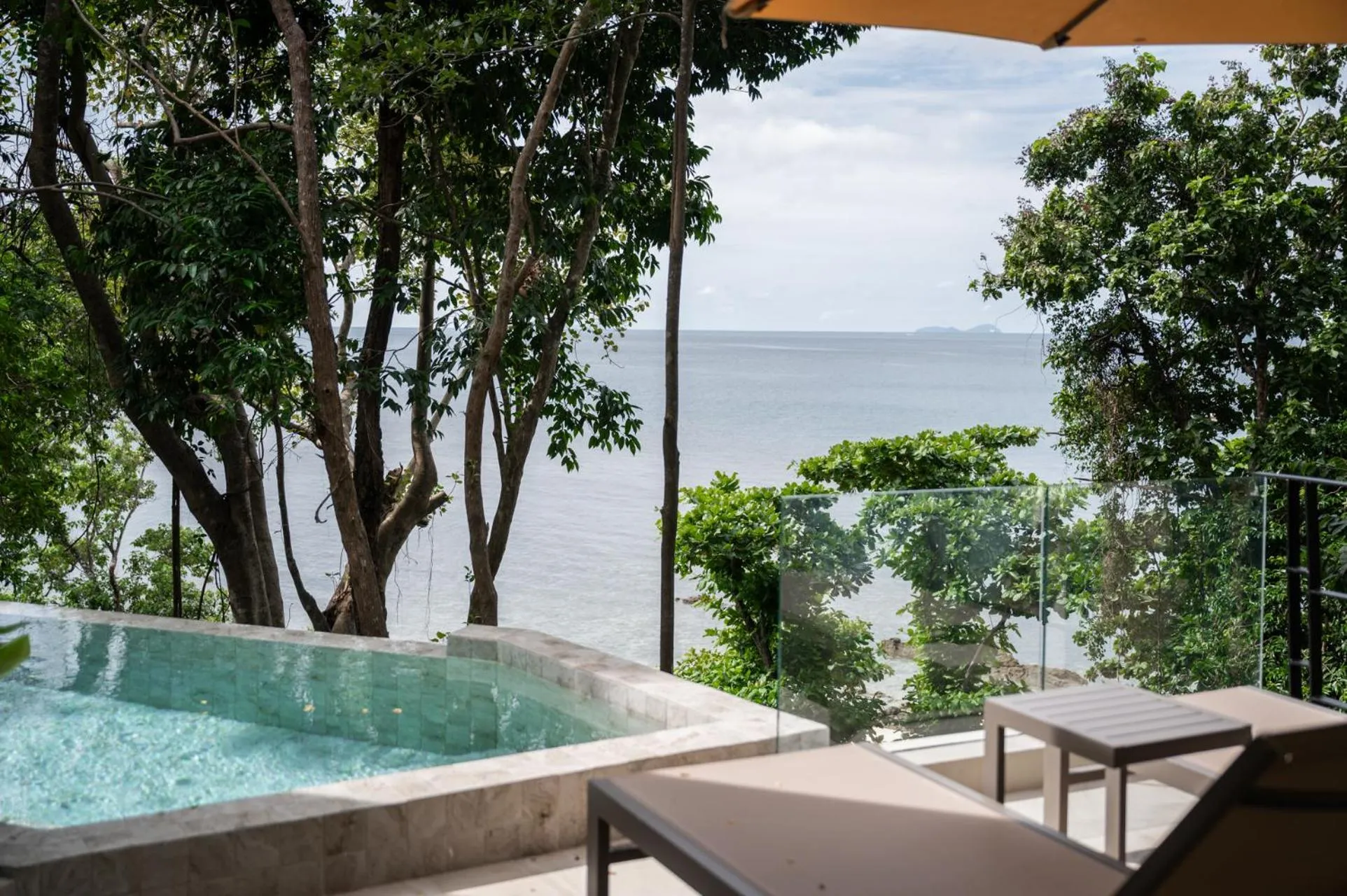 Petite piscine avec transats et vue sur la mer.