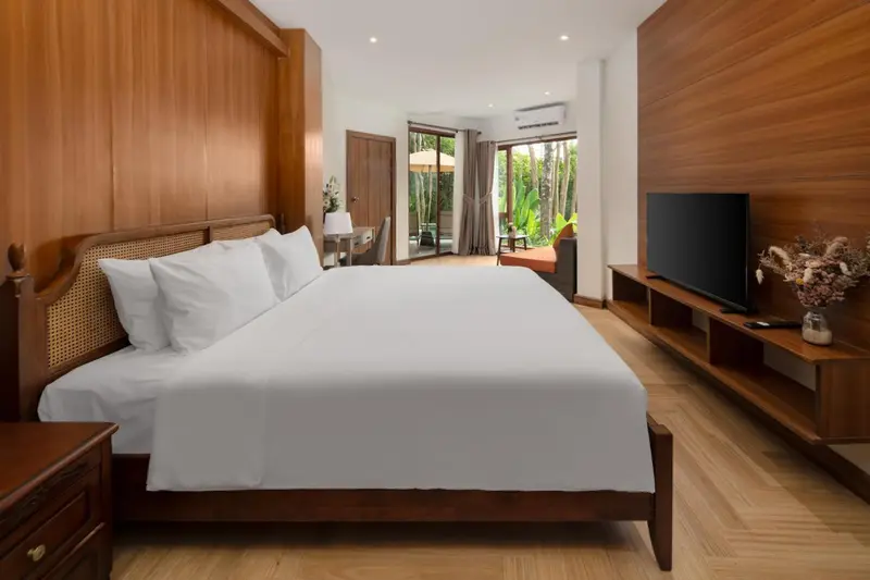 Une chambre lumineuse avec un grand lit et un téléviseur.
