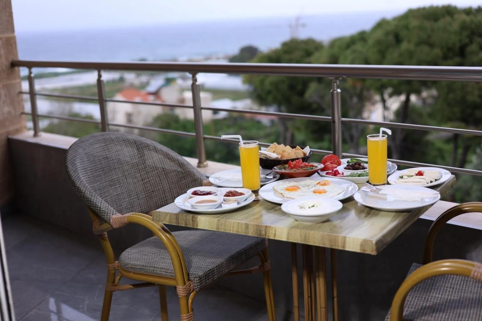 Une table de petit-déjeuner est dressée sur une terrasse avec vue sur la mer.