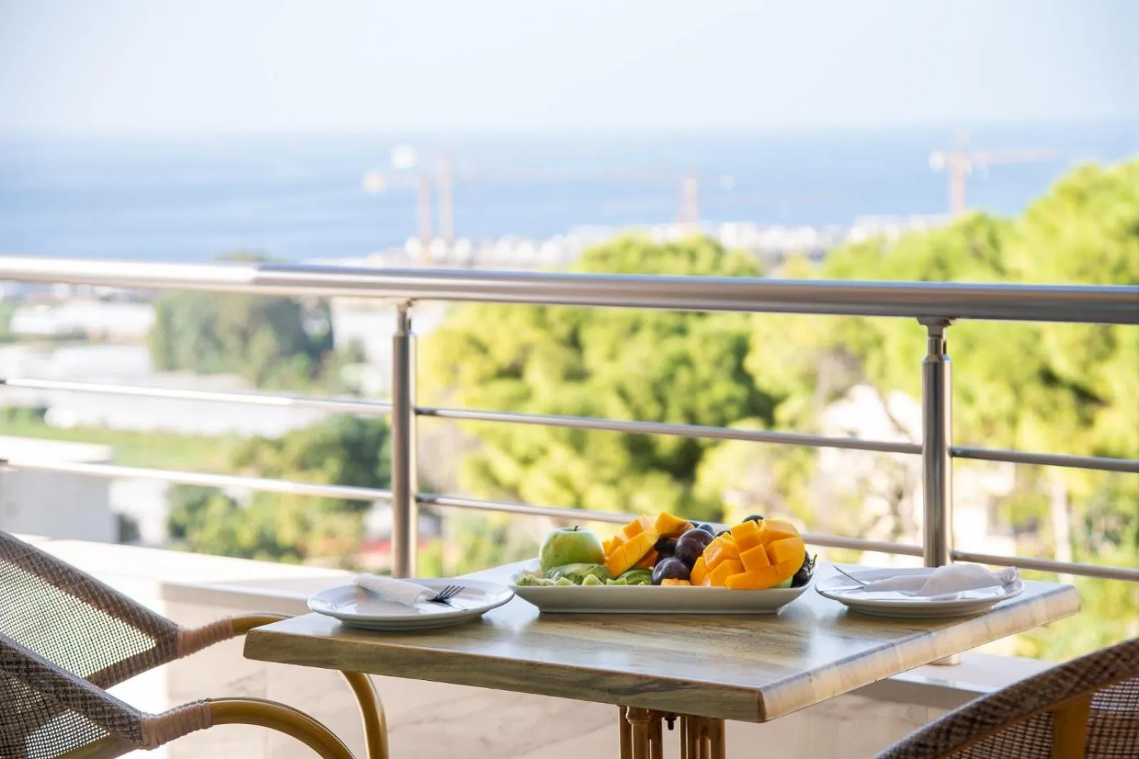 Une table avec des fruits frais est mise en scène sur une terrasse avec vue sur la mer.