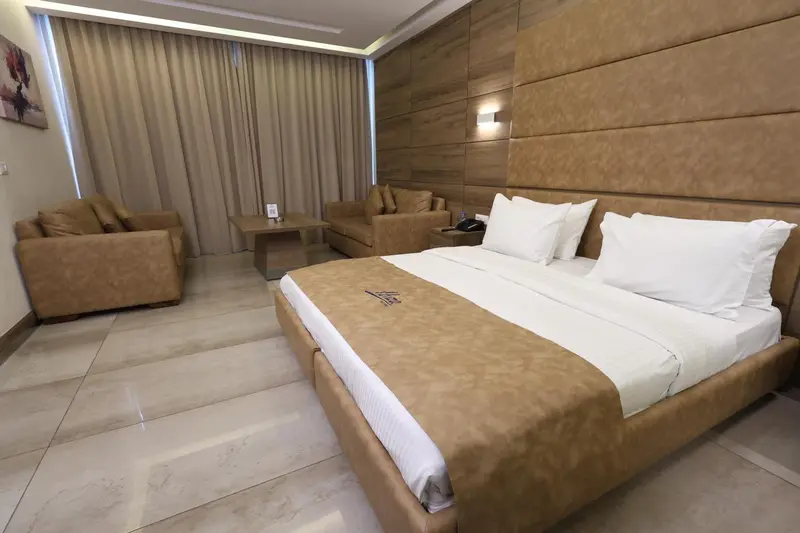 Une chambre lumineuse avec un lit double et un coin salon.