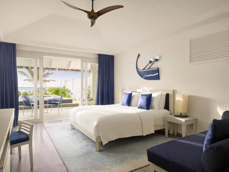 Chambre lumineuse avec un grand lit et vue sur la mer.