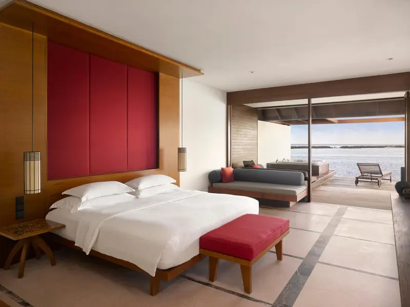 Une chambre lumineuse avec un grand lit et un espace salon donnant sur l'océan.