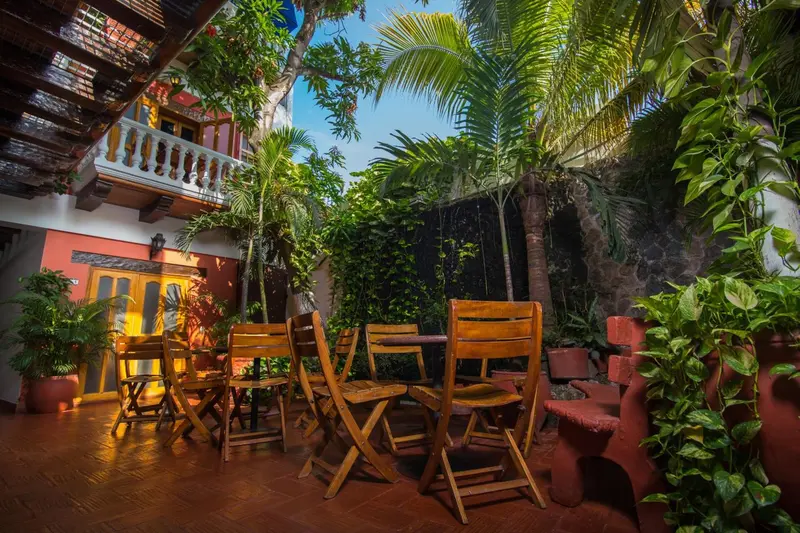 Terrasse ombragée avec mobilier en bois et végétation tropicale.