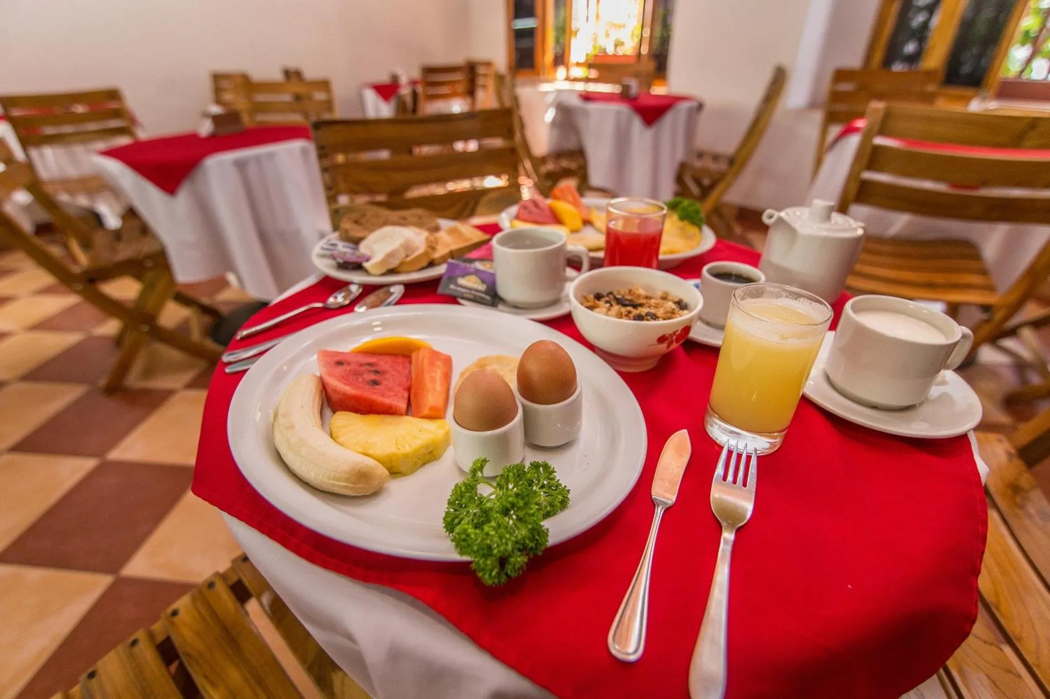 Une table est dressée pour le petit-déjeuner avec des fruits, des œufs et des boissons.