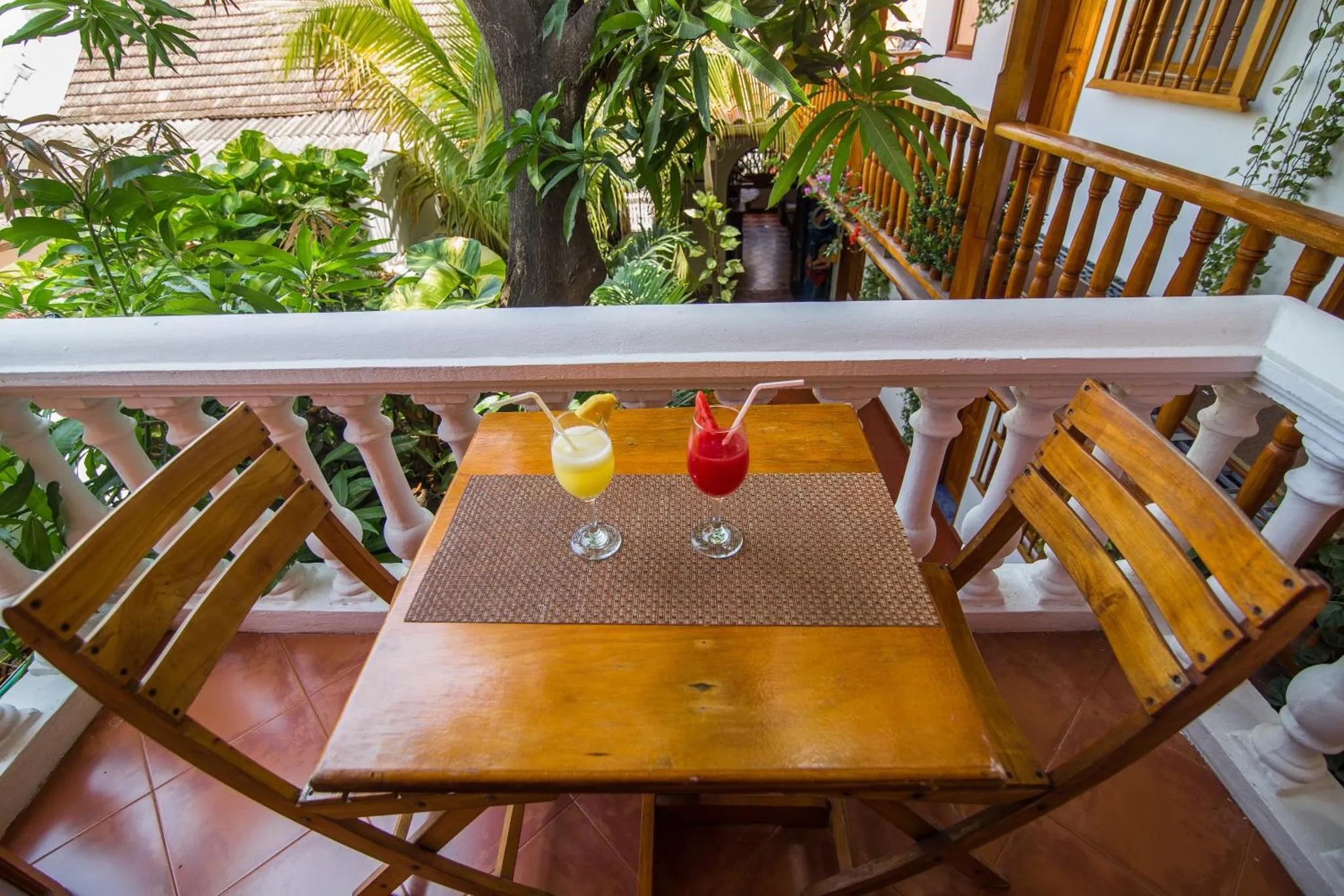 Une table avec deux cocktails colorés sur une terrasse en bois.