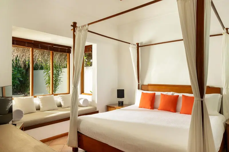 Une chambre lumineuse avec un lit à baldaquin et un coin salon.
