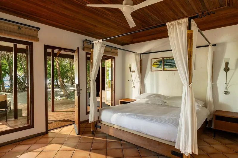 Une chambre lumineuse avec un lit à baldaquin donnant sur une végétation luxuriante.